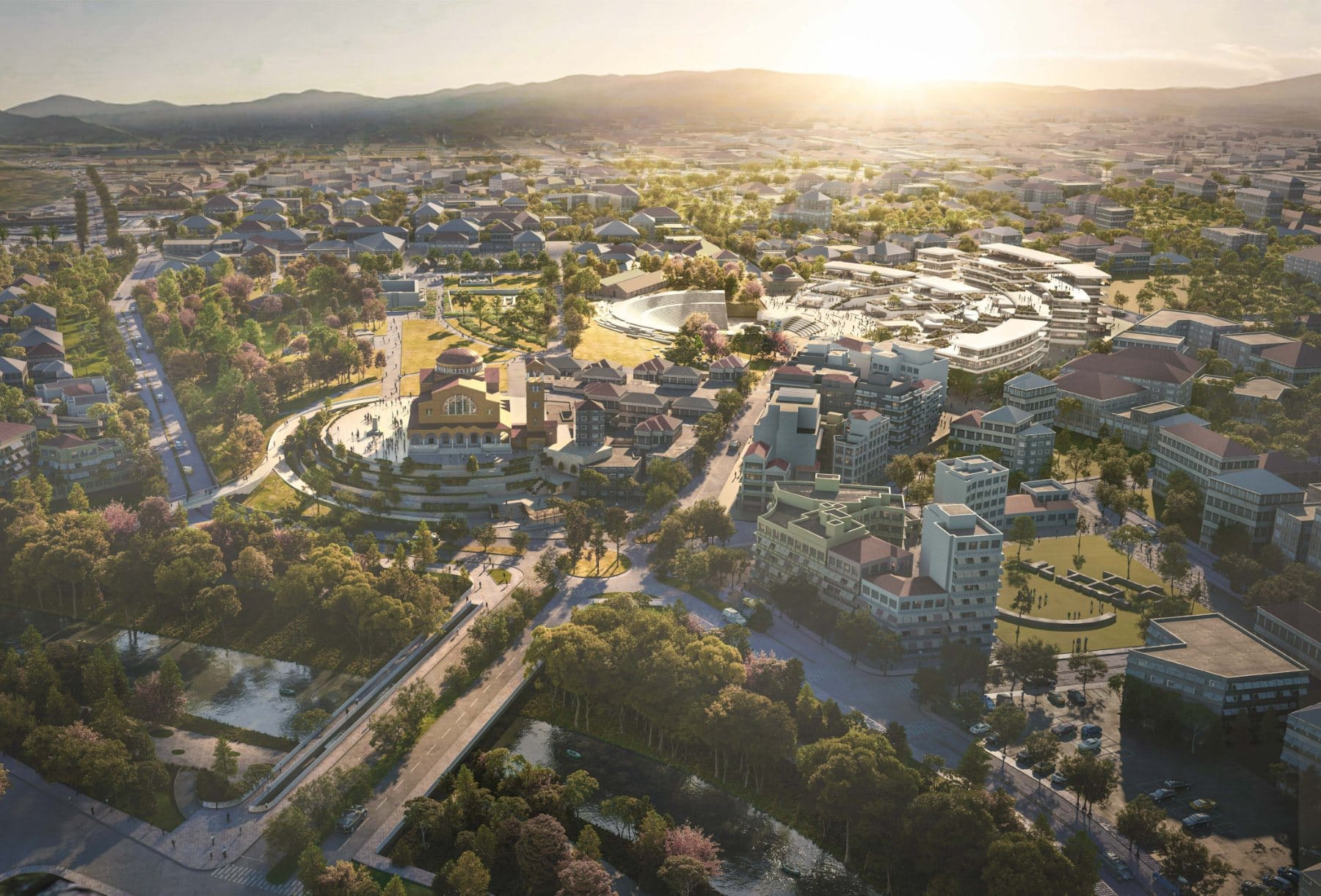 Aerial · the master plan at golden hour, anchored by the amphitheatre and Agios Achillios cathedral