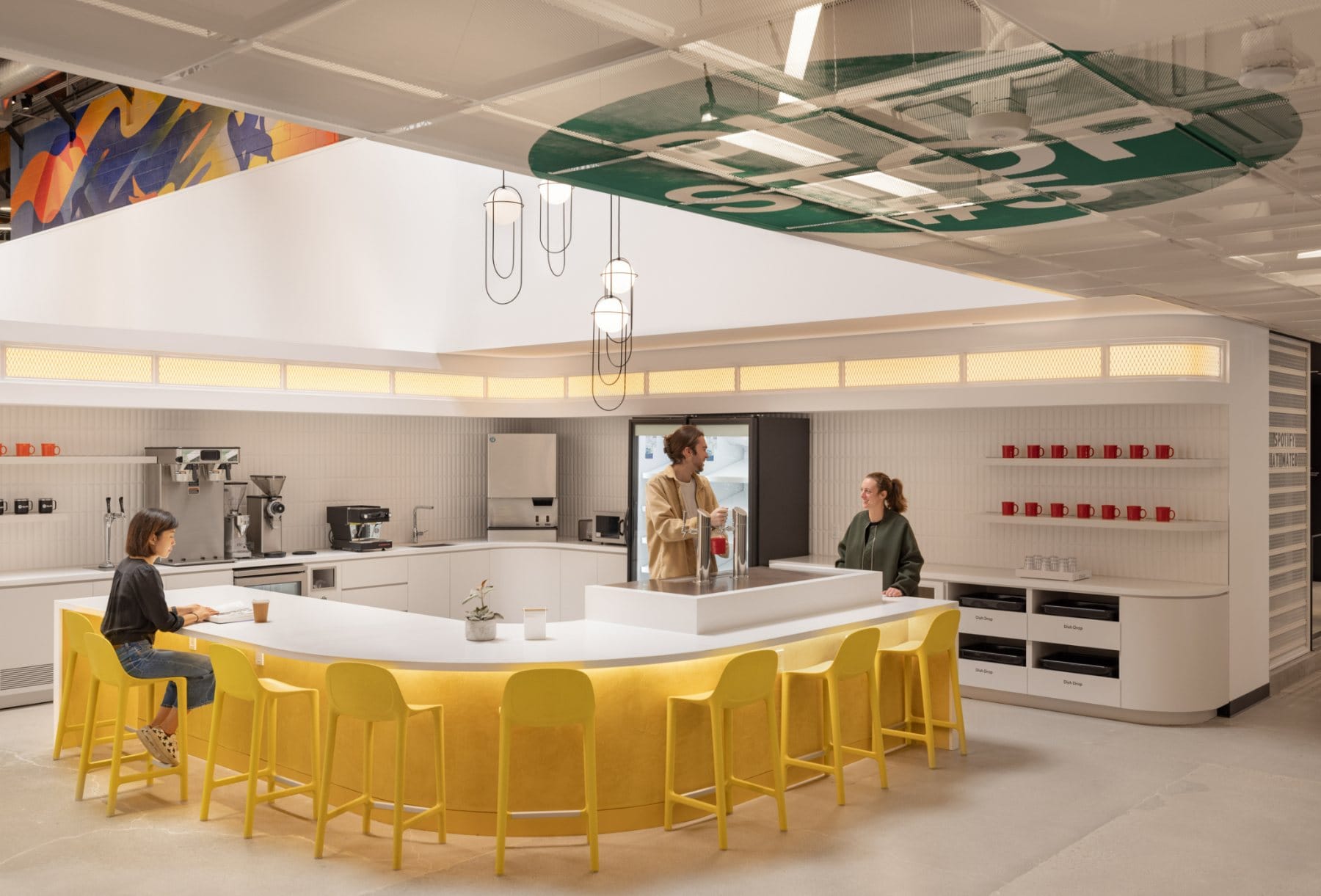 Collaboration lounge · modular seating and visible meeting rooms beyond the open work floor